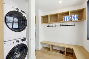 Laundry area with stacked washer / dryer, light wood-style flooring, and recessed lighting