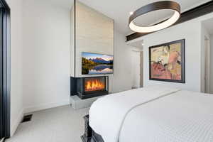 Bedroom with carpet and a lit fireplace