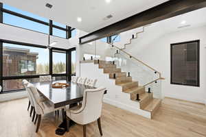 Dining area with plenty of natural light, a ceiling fan, light wood finished floors, recessed lighting, and a high ceiling