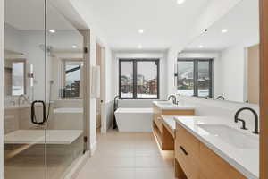 Bathroom with a freestanding tub, two vanities, a stall shower, light tile patterned floors, and recessed lighting
