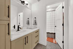 Full bathroom featuring a shower with shower curtain, vanity, and light tile patterned floors