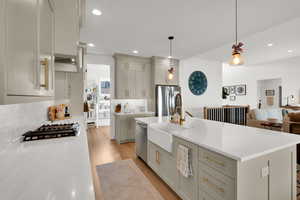 Kitchen with gray cabinets, hanging light fixtures, open floor plan, and light stone counters