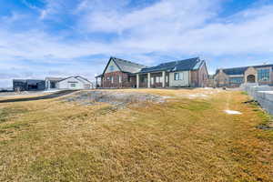 View of front facade with a patio area, brick siding, and a front lawn