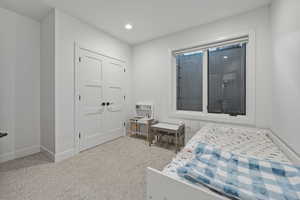 Bedroom with a closet, light colored carpet, and recessed lighting