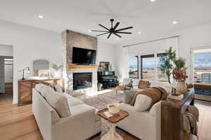 Living area with a fireplace, light wood-type flooring, a ceiling fan, and recessed lighting