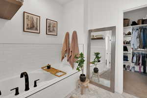 Bathroom featuring a walk in closet and a bath