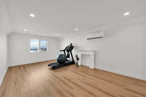 Exercise room with lofted ceiling, recessed lighting, and light wood finished floors