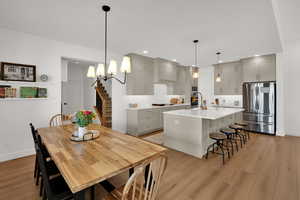 Kitchen with a kitchen breakfast bar, stainless steel appliances, gray cabinets, and light wood-style floors