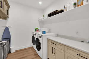 Laundry room featuring cabinet space, light wood finished floors, separate washer and dryer, and recessed lighting