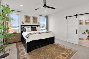 Bedroom with a barn door, carpet, a ceiling fan, and recessed lighting