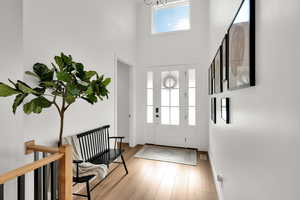 Foyer with a high ceiling, light wood-type flooring, and suspended lighting
