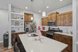 Kitchen featuring pendant lighting, stainless steel appliances, decorative backsplash, a breakfast bar area, and a kitchen island with sink