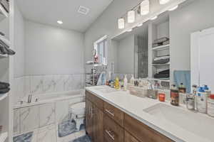 Bathroom featuring double vanity, a garden tub, and a shower stall