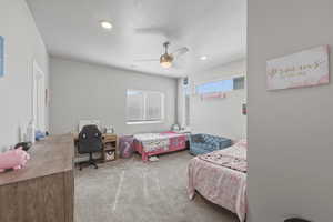 Carpeted bedroom with a desk, a ceiling fan, and recessed lighting