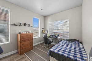 Bedroom with a desk and dark wood-style flooring