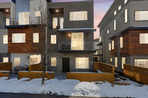 View of front facade with a balcony, stucco siding, and stone siding