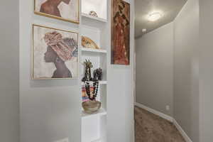 Corridor featuring light colored carpet and a textured ceiling
