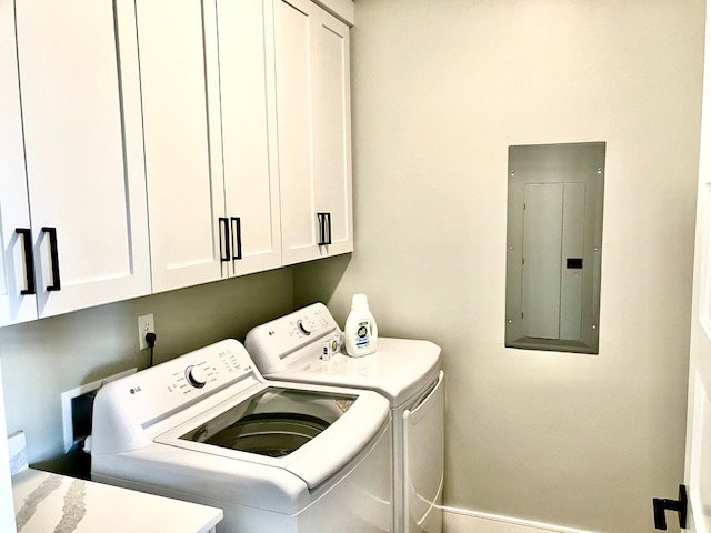 Laundry room featuring cabinet space, electric panel, and washing machine and clothes dryer