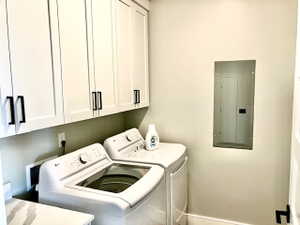 Laundry room featuring cabinet space, electric panel, and washing machine and clothes dryer