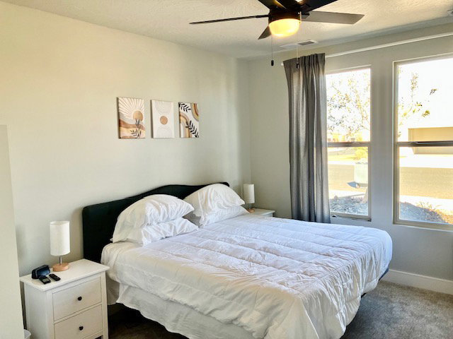 Bedroom with a ceiling fan and dark carpet