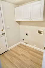 Laundry area featuring hookup for a gas dryer, hookup for a washing machine, light wood-style floors, cabinet space, and electric dryer hookup