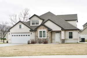 View of front of house with roof with shingles, concrete driveway, stucco siding, stone siding, and a garage