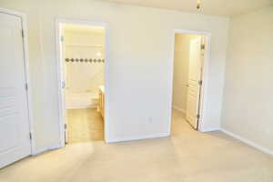 Unfurnished bedroom featuring light carpet and ensuite bathroom