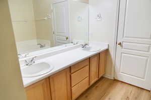 Master bathroom featuring double vanity, light wood finished floors, and a bath