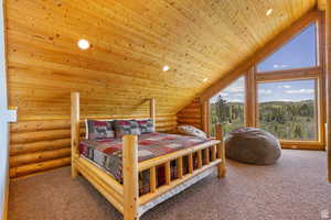 Carpeted bedroom featuring log walls, a vaulted wooden ceiling, and recessed lighting