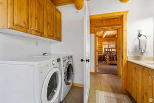 Laundry area featuring rustic walls, cabinet space, washing machine and dryer, and light tile patterned floors