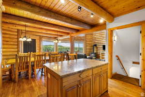 Kitchen with a wood stove, wood finish cabinets, light stone countertops, light wood-style floors, and hanging lights