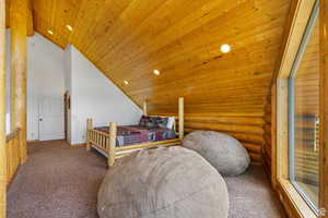 Carpeted bedroom with rustic walls, a vaulted wood ceiling, and recessed lighting