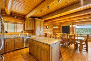 Kitchen with light stone counters, wood finish cabinetry, a center island, stainless steel appliances, and rustic walls