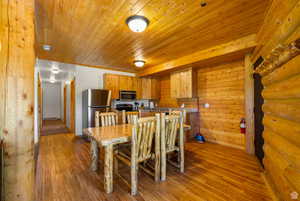 Dining area featuring log walls, wood finished floors, wooden walls, and wood ceiling