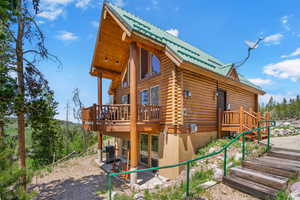 View of side of home with a metal roof, log exterior, a deck, and a patio
