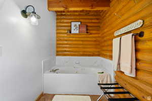 Full bathroom featuring a tub with jets and log walls