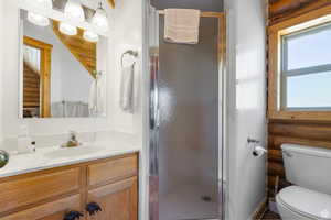 Full bathroom with a stall shower, vanity, and rustic walls