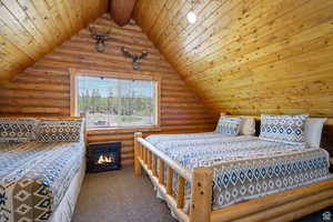 Bedroom featuring log walls, carpet, wooden ceiling, and vaulted ceiling with beams