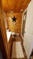 Full bath featuring wooden walls, vanity, a shower stall, wooden ceiling, and baseboard heating