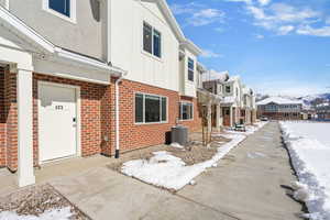 View of snowy exterior with a residential view, brick siding, and board and batten siding