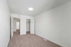 Unfurnished bedroom with a walk in closet and light carpet