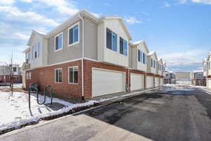 View of property exterior featuring brick siding, board and batten siding, a garage, and a residential view