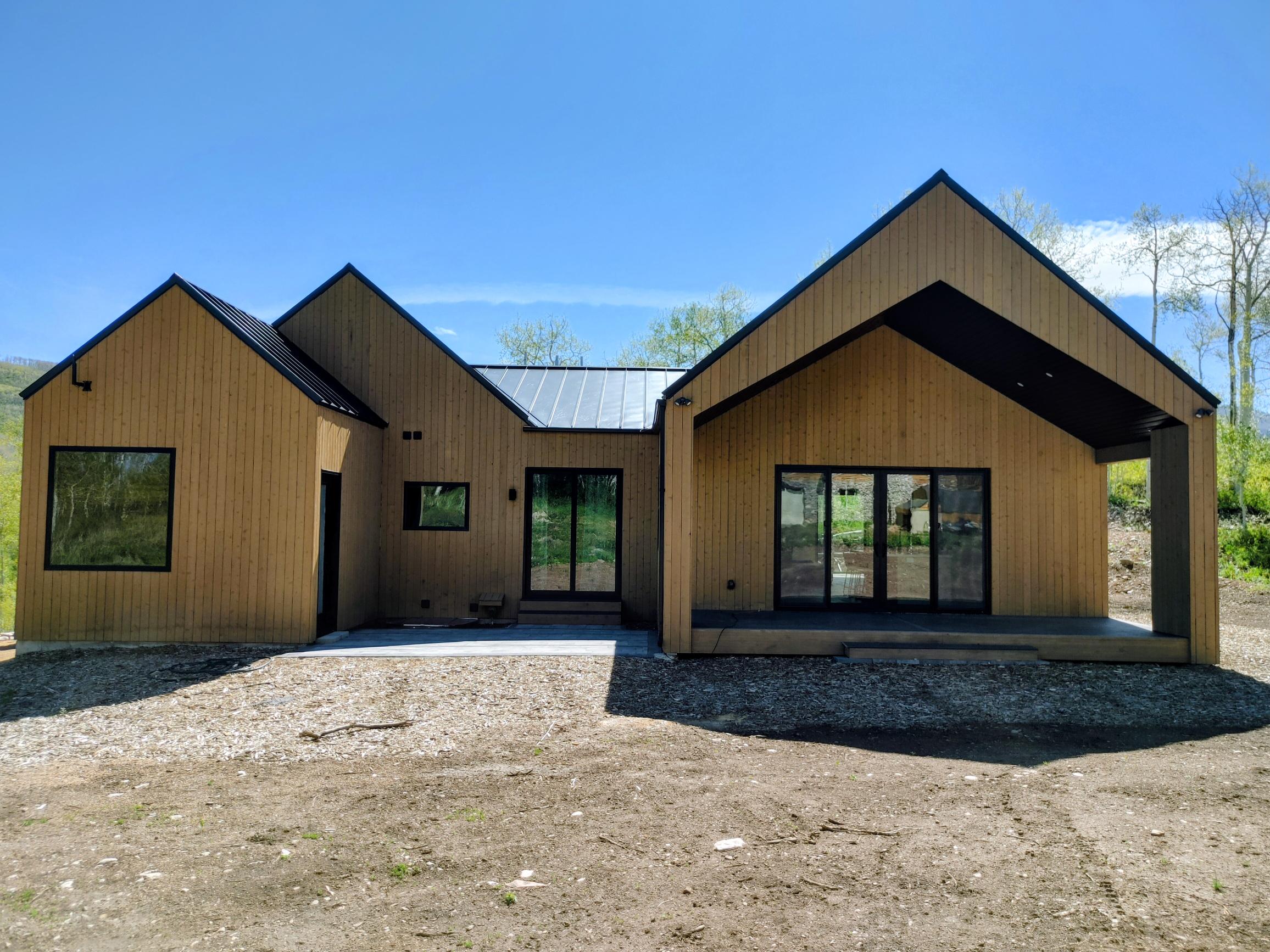 Modern architectural design featuring natural wood siding and a black metal roof