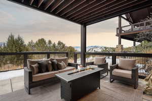 Deck at dusk featuring an outdoor living space with a fire pit, a patio area, and a mountain view