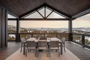 Snow covered deck with a mountain view and outdoor dining space