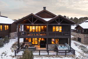 Snow covered rear of property with a patio area, board and batten siding, and stone siding