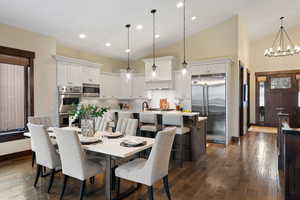 Dining room featuring dark wood-type flooring, hanging lights, and lofted ceiling