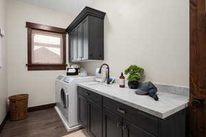 Laundry area featuring dark wood finished floors, cabinet space, and washer and clothes dryer