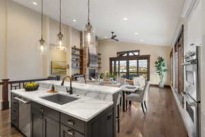 Kitchen featuring pendant lighting, ceiling fan, light stone countertops, open floor plan, and stainless steel appliances