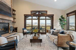 Living area featuring a mountain view, a stone fireplace, and vaulted ceiling